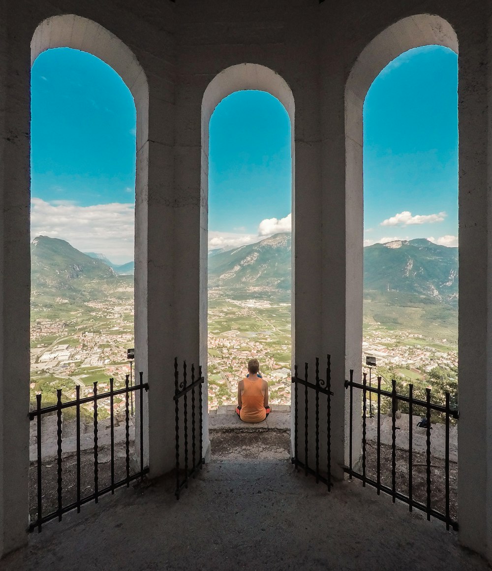 person sitting on brown flooring while staring at mountain