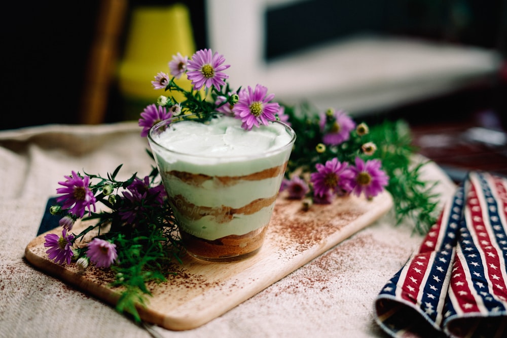 ice cream on drinking glass beside purple flowers