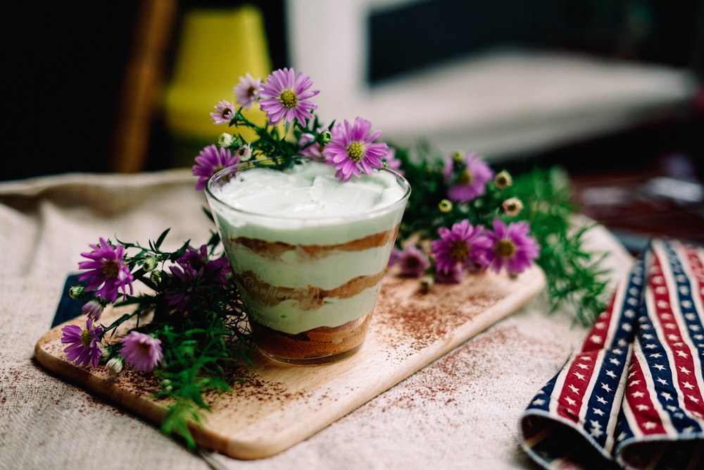 crème glacée sur verre à boire à côté de fleurs violettes
