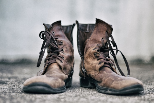 Classic brown leather boots with rugged soles, set against a rustic wooden background.