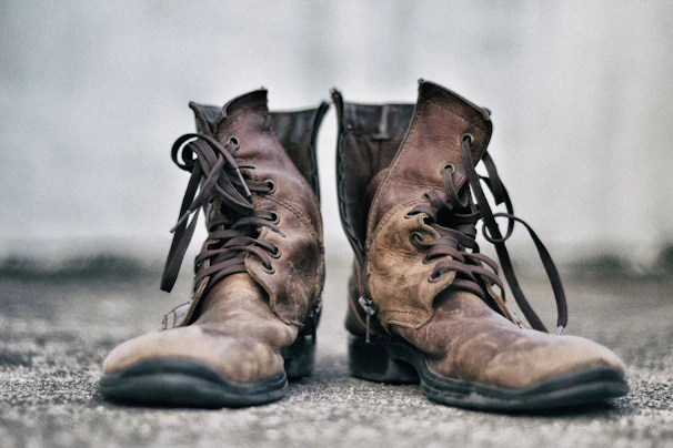 Close-up of rugged combat boots and gloves on a textured wooden surface.