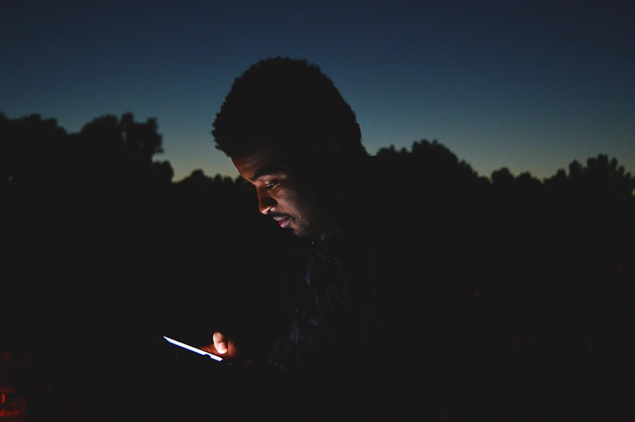 Field photo: a man at dusk, face lit only by his phone screen
