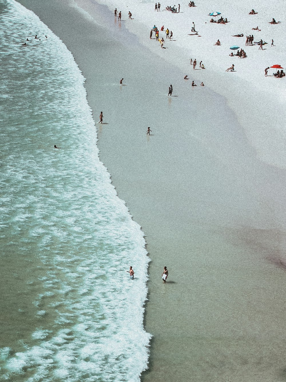 Photographie aérienne de personnes sur une plage de sable blanc