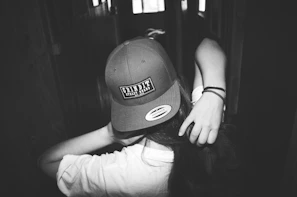 Black and white shot of a model adjusting a cap with strong contrast