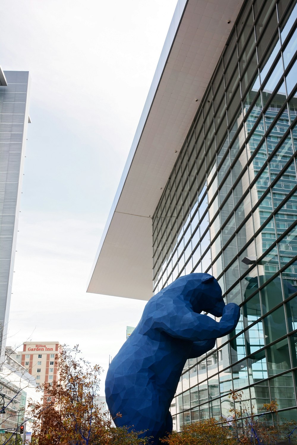 urso azul apoiado em edifício de vidro