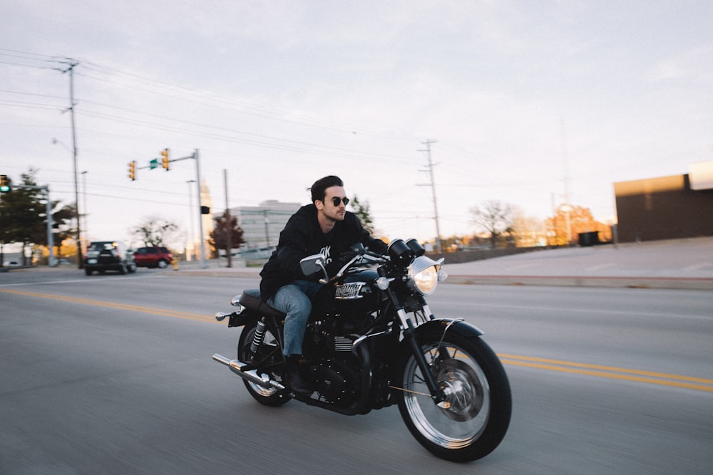 Homem pilotando motocicleta cruiser na estrada durante o dia