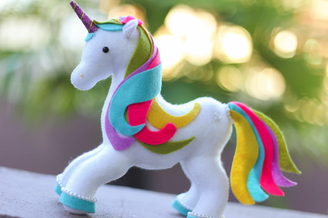 Close-up of a pastel pink crocheted unicorn with soft detailing.