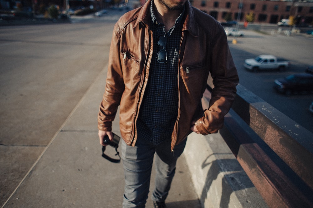 man wearing leather jacket walking beside street