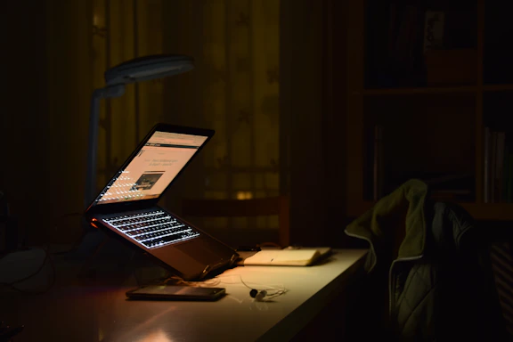 A dimly lit office desk with scattered paperwork and a phone showing a social media app, symbolizing distraction and poor security.