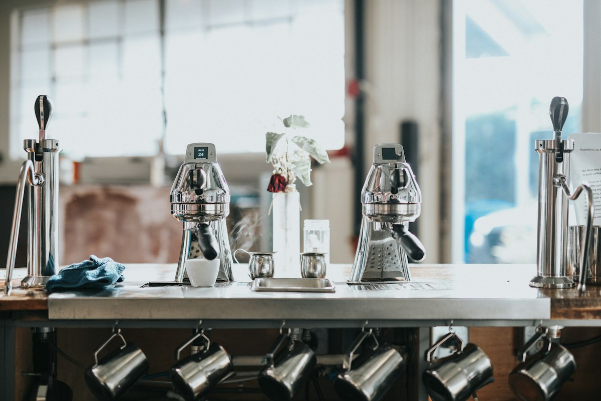 Two stainless steel espresso machines on a cafe counter