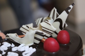 A close-up of a chocolate layer cake with glossy ganache and decorative swirls.