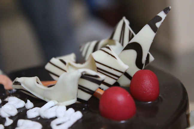 Close-up of a luxurious black forest cake with glossy cherries and rich buttercream swirls.