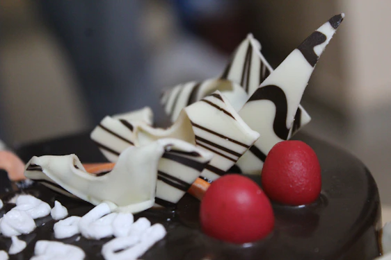 A close-up of a beautifully decorated chocolate cake with fresh berries and delicate frosting swirls.