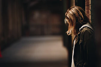 woman leaning against a wall in dim hallway