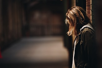 woman leaning against a wall in dim hallway