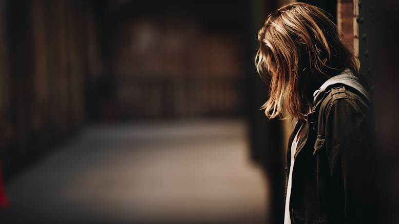 woman leaning against a wall in dim hallway