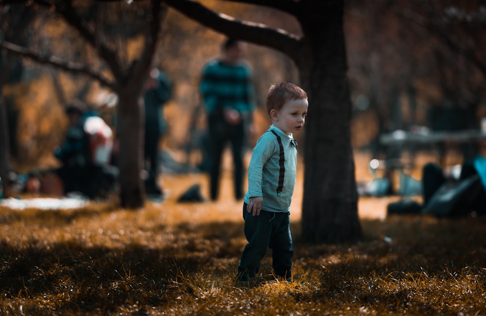 baby boy standing on grass near trees