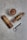 A cup of frothy coffee is placed on a textured surface alongside three cigars neatly wrapped in decorative bands and arranged in a row. A sleek metal cigar cutter with a ring handle lies nearby, suggesting a theme of relaxation and luxury.
