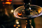 A close-up of glowing bakhoor pieces on a decorative incense burner.