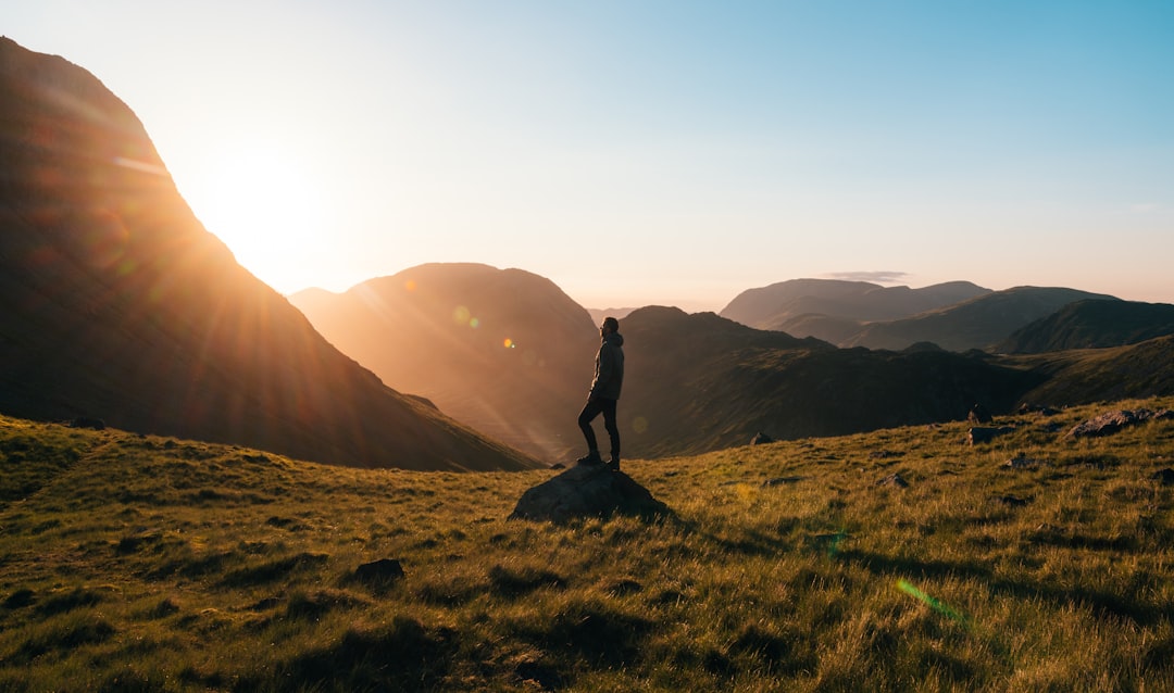 man standing on top of rock in an open field at golden hour