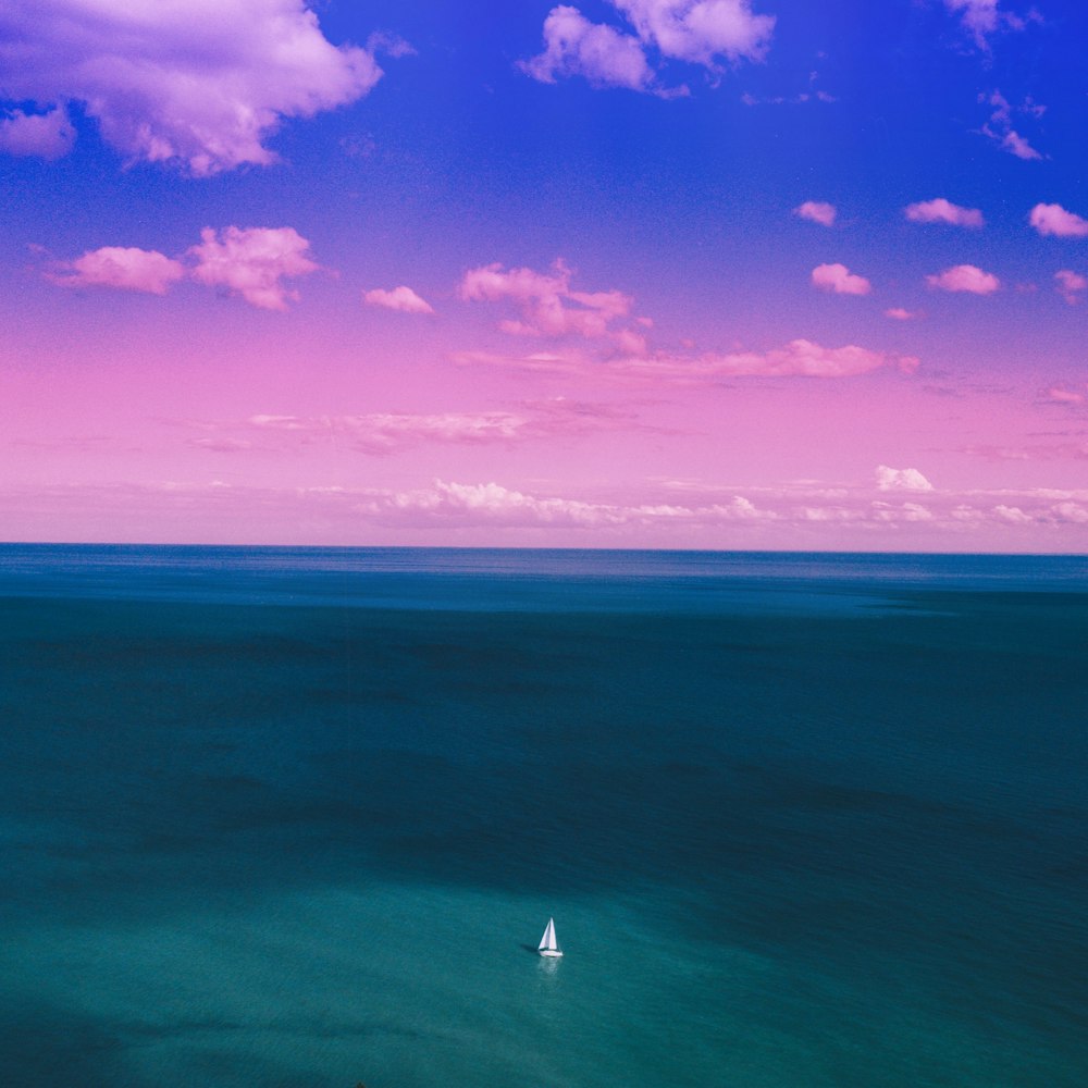 紫と青の空の下、青い海に浮かぶヨット