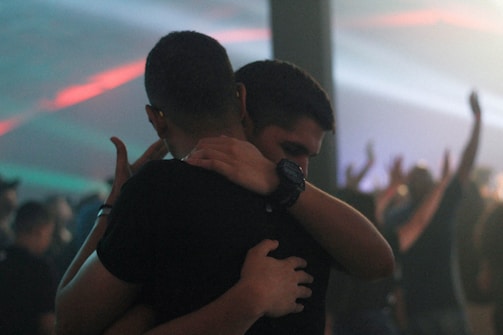 two men hugging each other inside bar