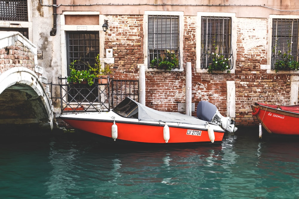 red motorboat beside rails on body of water