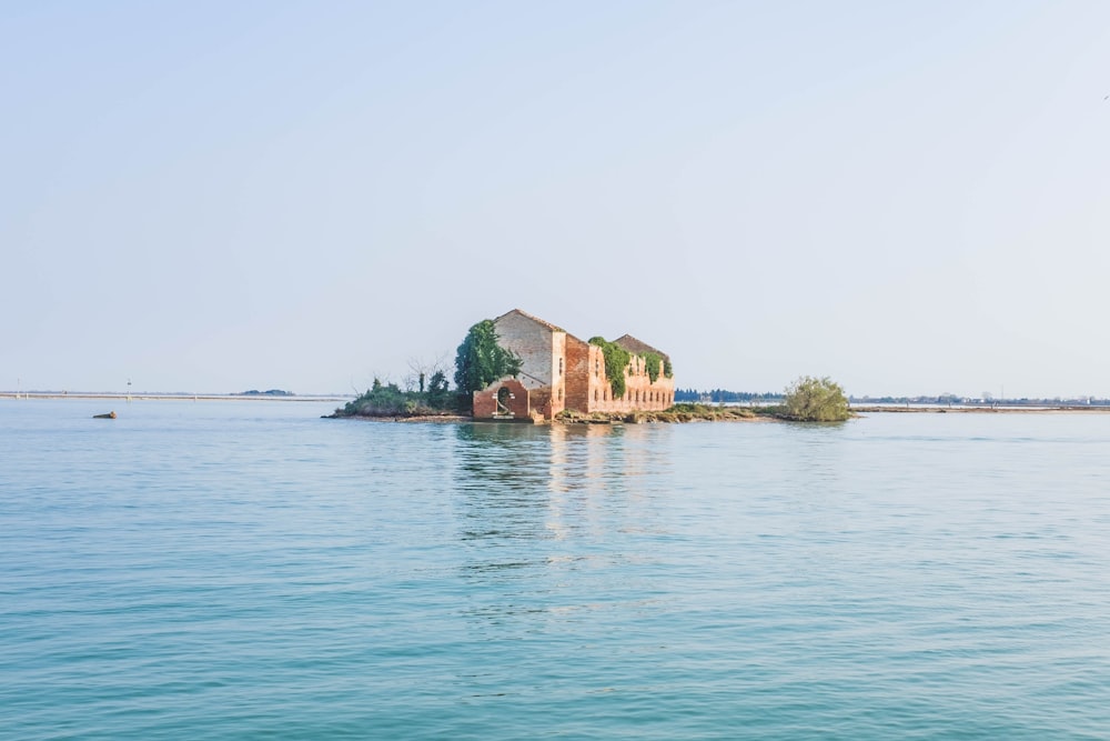 beige and red concrete house surrounded by body of water