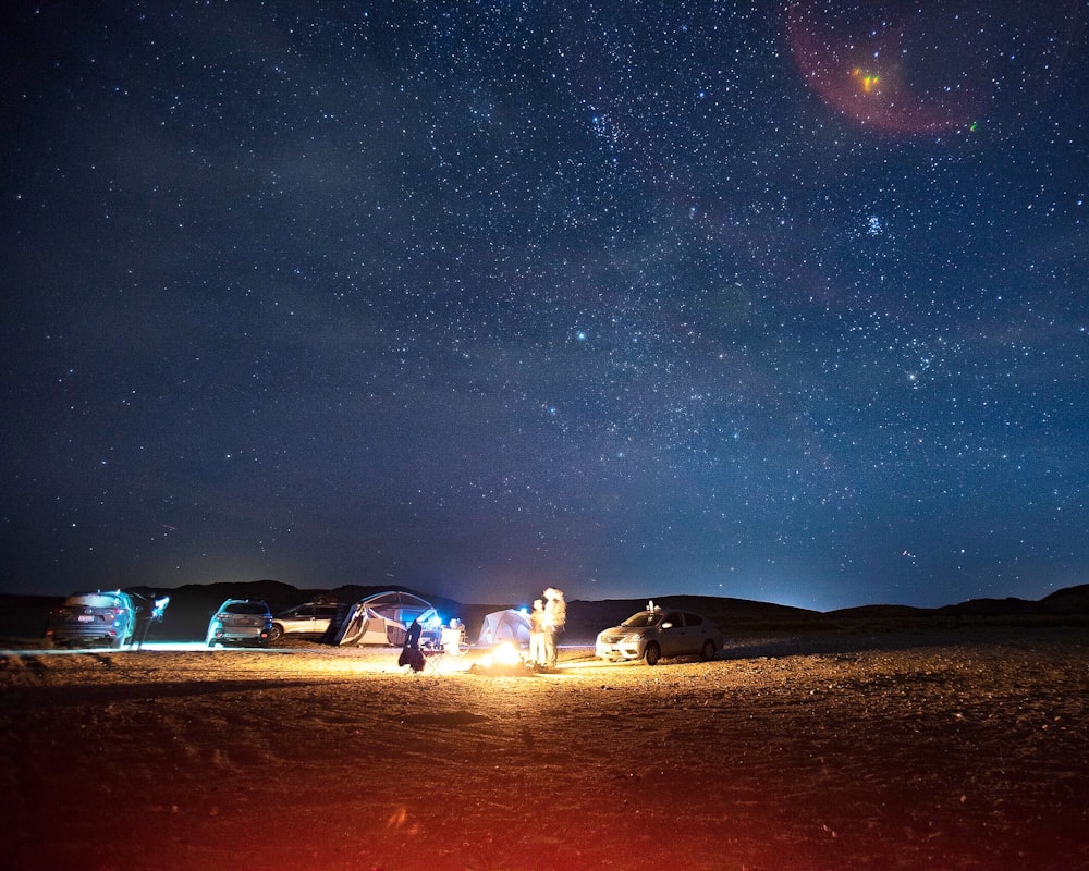 Fuoco acceso vicino all'auto e alla tenda a cupola durante la notte