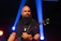 A candid photo of Sonoravibe performing passionately with guitar under warm stage lights.