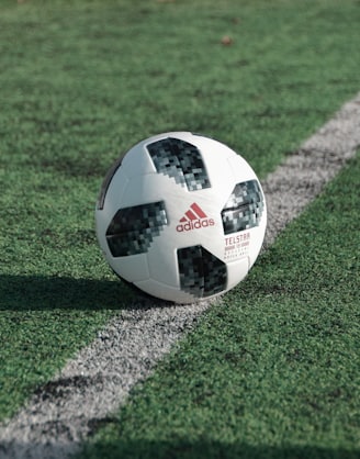 close-up photography of adidas soccer ball on field