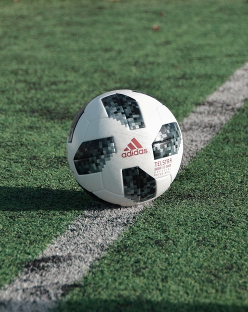 close-up photography of adidas soccer ball on field