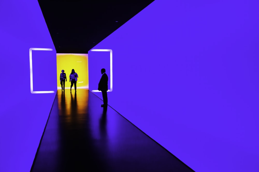 three person standing near wall inside building