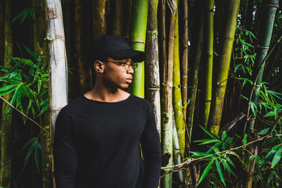 man standing front of bamboo tree while looking sideward