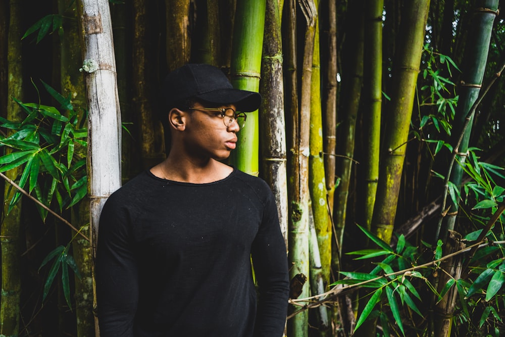 man standing front of bamboo tree while looking sideward