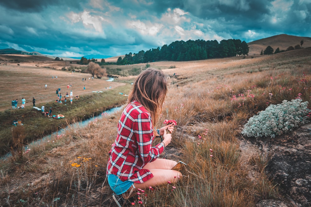 woman holding red flower during daytime