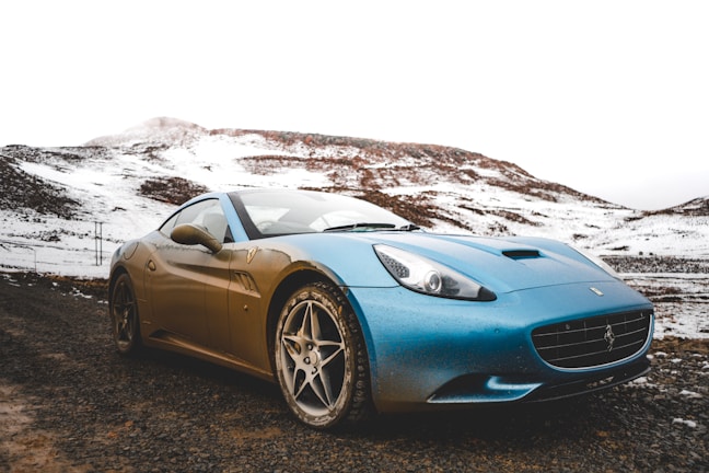 A stunning blue coupe against a scenic mountain backdrop.