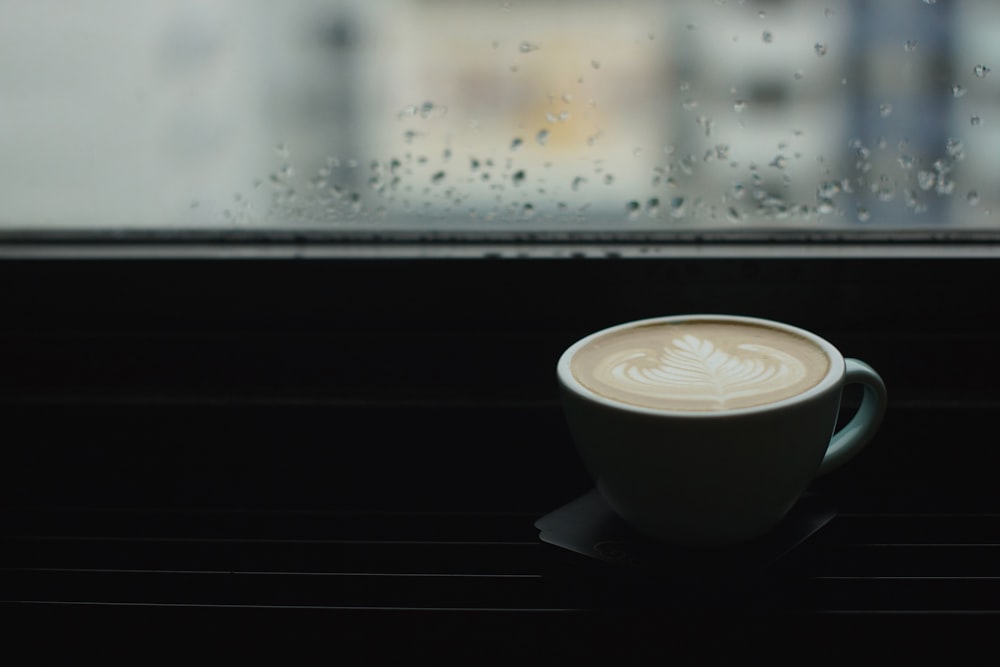 blue ceramic teacup beside window pane