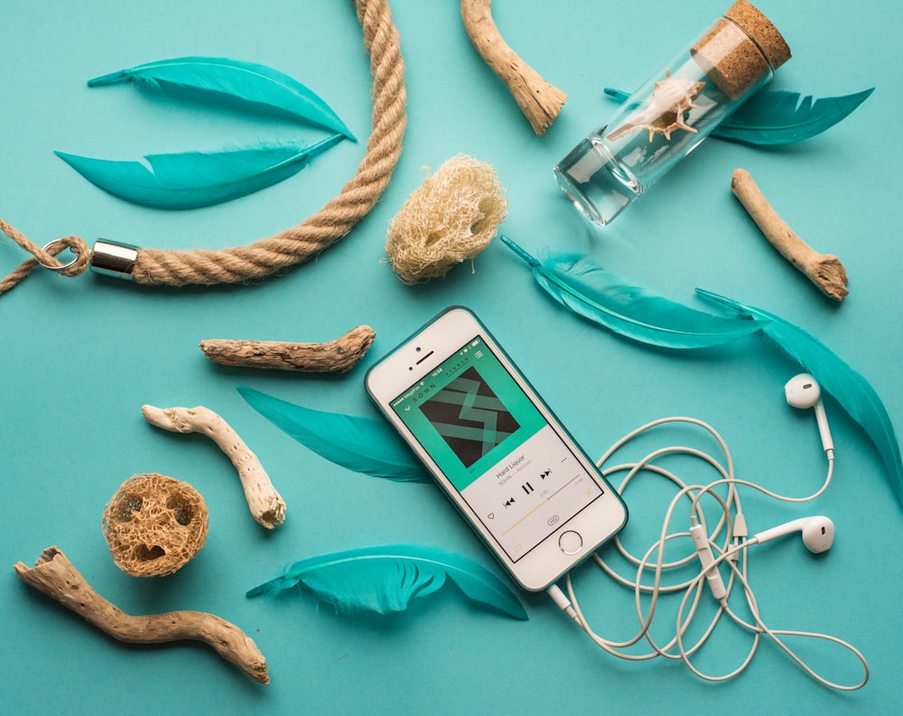 iPhone con EarPods junto a plumas y adornos