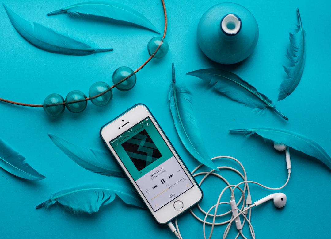 iPhone with EarPods beside feathers, Turquoise