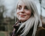 white haired woman standing near trees