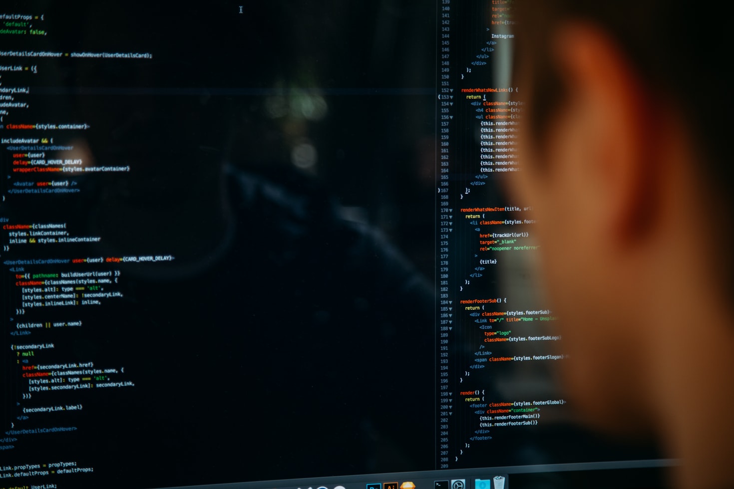 Person, out of focus, looking at code on a computer screen.