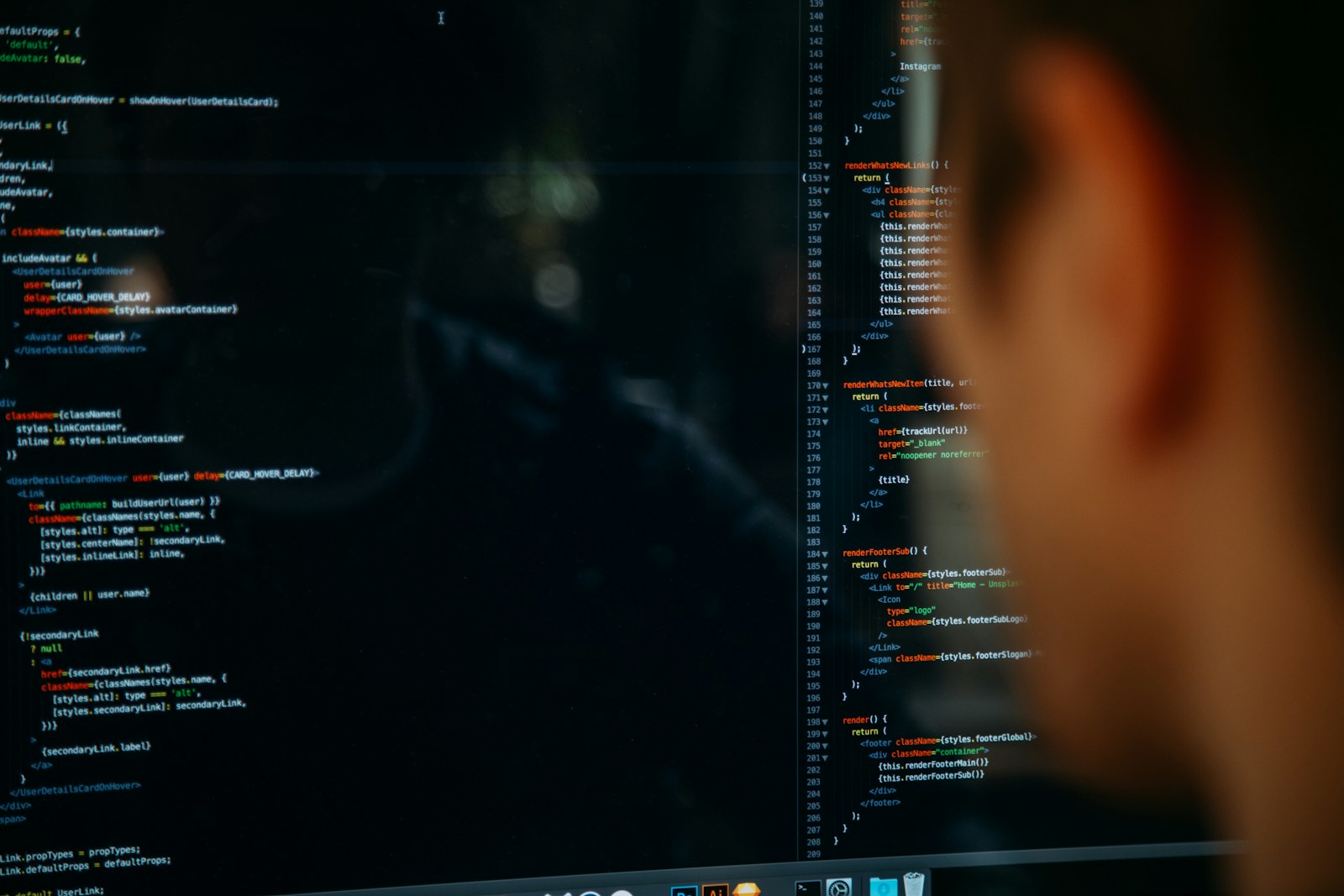 A person facing a desktop computer in a dim room