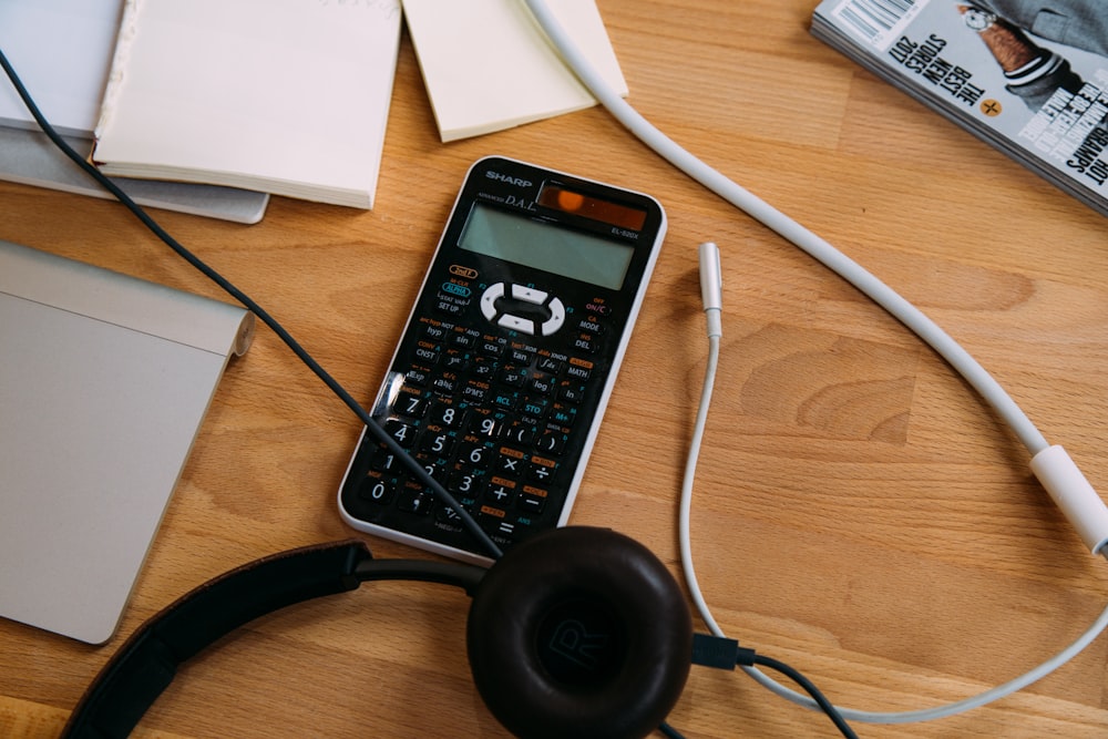 calculadora científica preta ao lado de fones de ouvido pretos