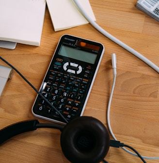 black scientific calculator beside black headphones