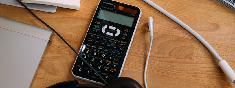 black scientific calculator beside black headphones