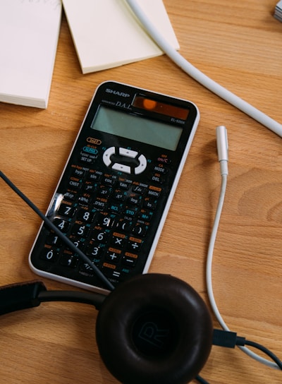 black scientific calculator beside black headphones