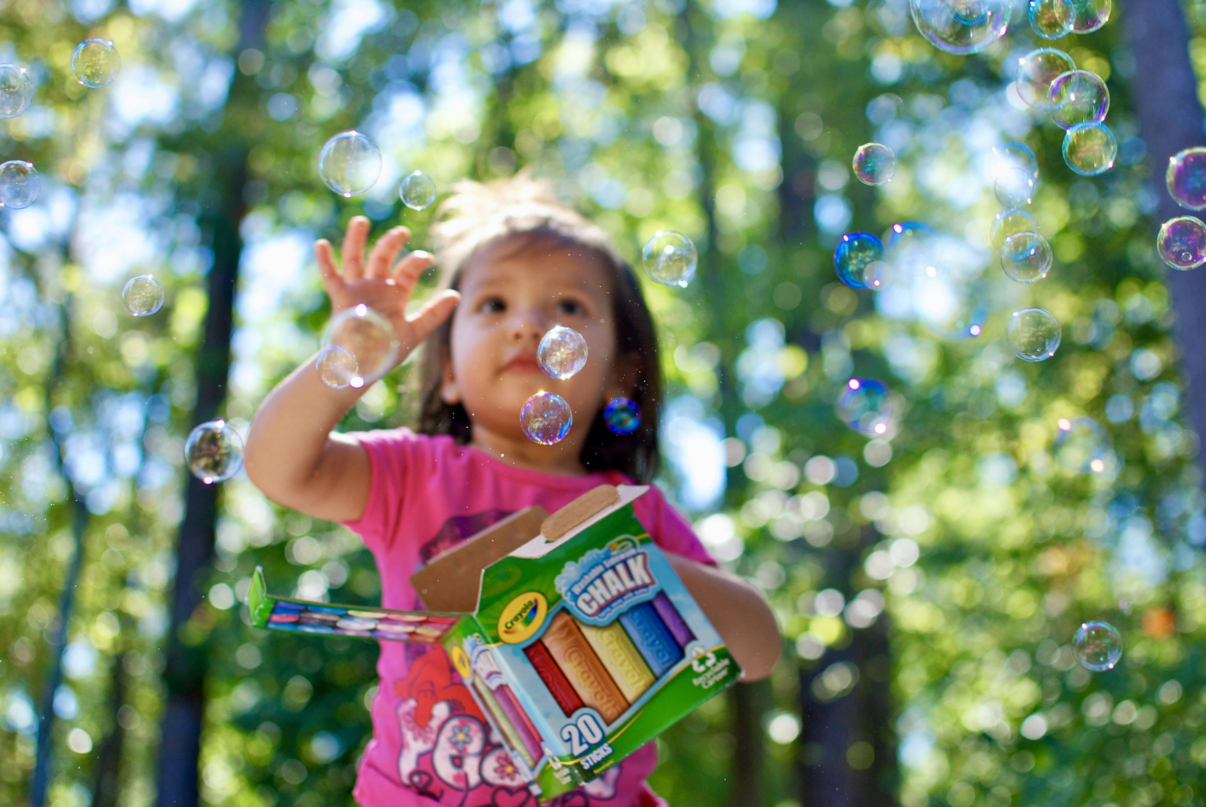 Close-up of colourful foam bubbles in soft pastel pink and white, child hands playing and squishing with delight