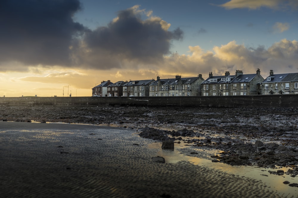 white-and-gray house near mud land under cloudy sky