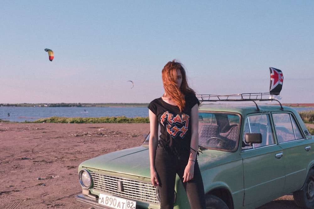 woman standing near blue car on seashore